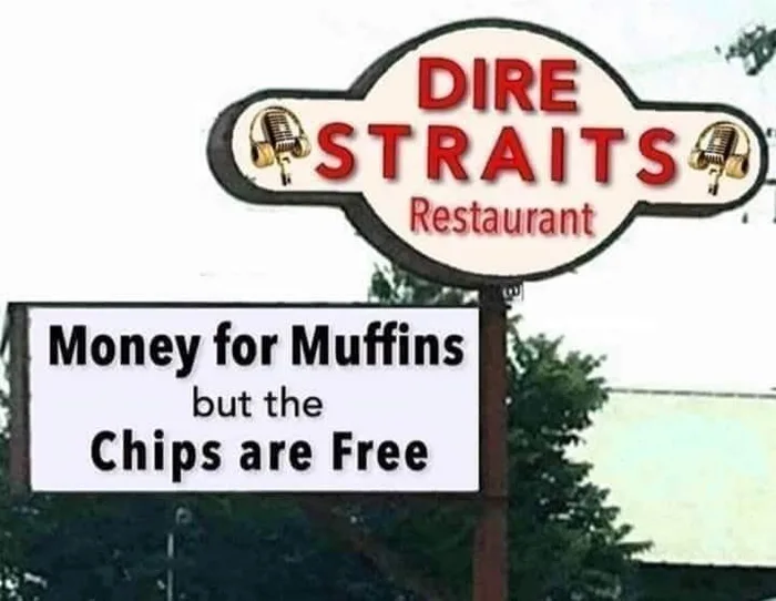 A roadside sign for Dire Straits Restaurant reading 'Money for Muffins but the Chips are Free'