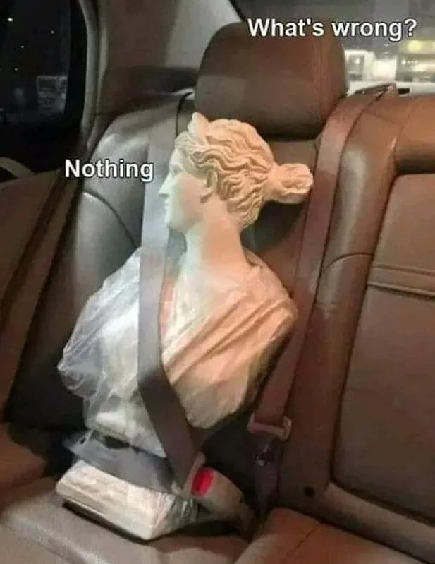A classical statue bust buckled into a car's back seat looking stiffly out the window, captioned 'What's wrong?' and 'Nothing'.