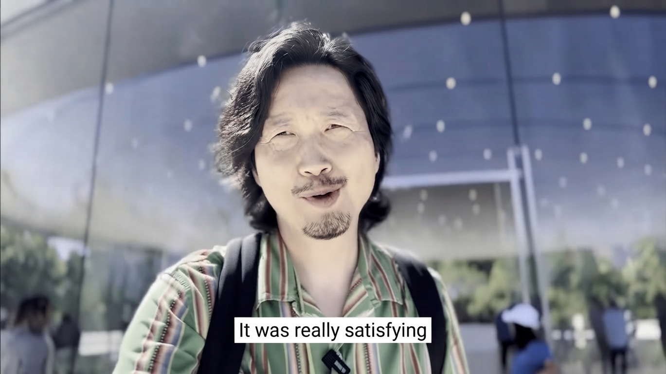Video capture of a man smiling in front of an outdoor building with a subtitle that reads, 'It was really satisfying.'