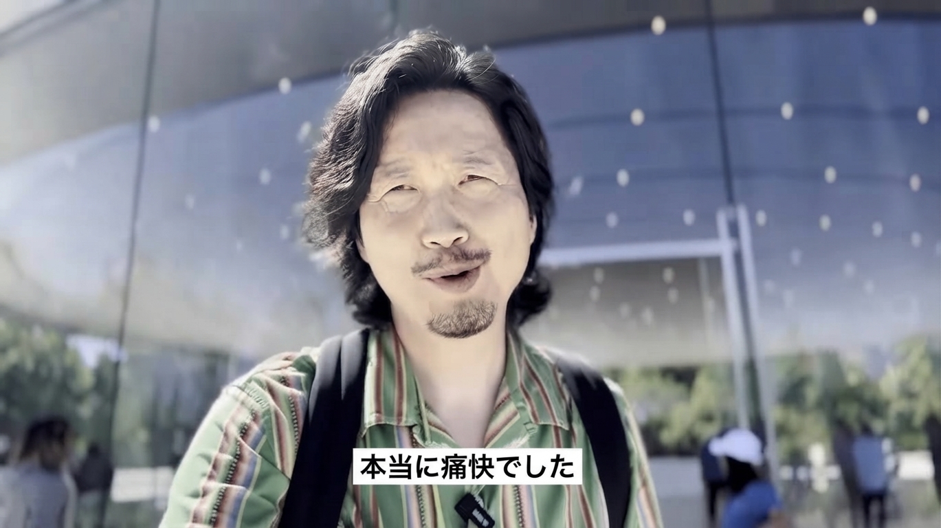 屋外の建物の前で男性が微笑みながら「本当に痛快でした」と話す字幕付きの動画キャプチャ画面。