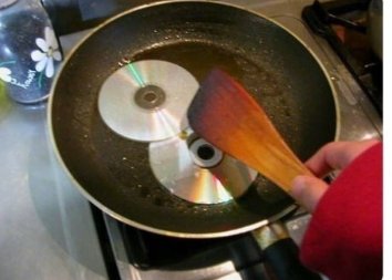 フライパンの上でCDを2枚、ヘラで焼いている古典的なユーモア画像