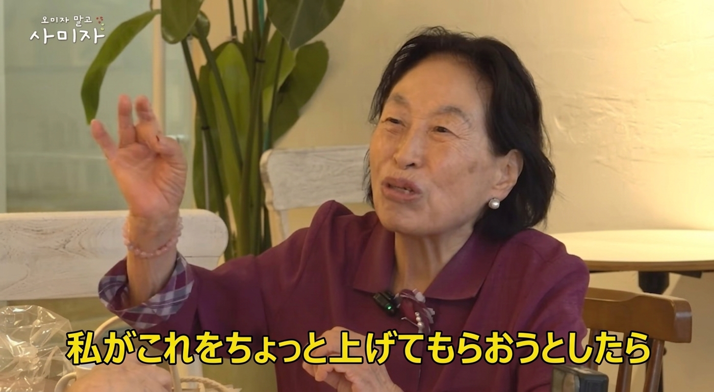 YouTube動画でチョン・ウォンジュが指でお金の形を作り、「私がこれ（お金）をちょっと上げてもらおうとしたら」と話している場面。