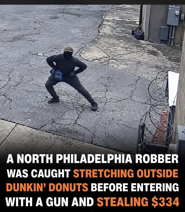 Security camera snapshot of a masked robber doing leg stretches outside a Dunkin' Donuts before committing a robbery.