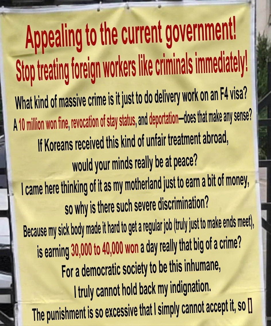 A yellow protest banner hanging on a metal fence with the headline 'Appealing to the current government! Stop treating foreign workers like criminals immediately!' featuring a long message claiming unfairness over receiving a 10 million won fine and deportation after being caught doing delivery work on an F-4 visa.