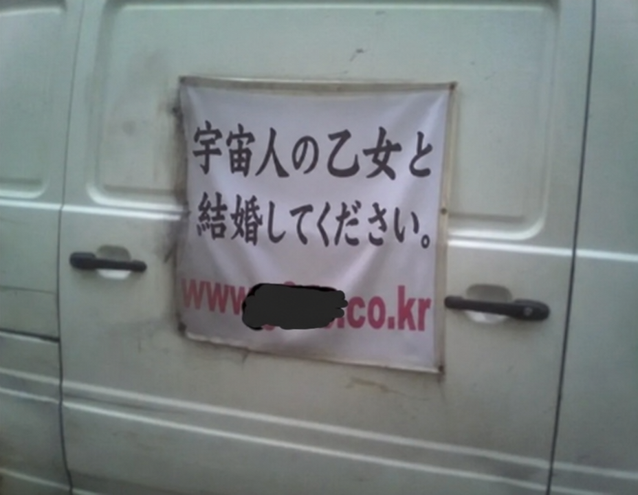 車両の後部ドアに掛けられた横断幕に「エイリアンの処女と結婚してください」というとんでもない誤字が書かれている様子