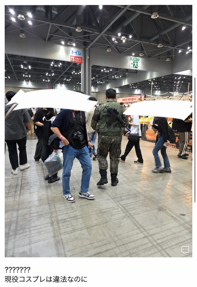 イベント会場内で軍服を着て模型の銃を背負ったまま歩いている人の後ろ姿の写真