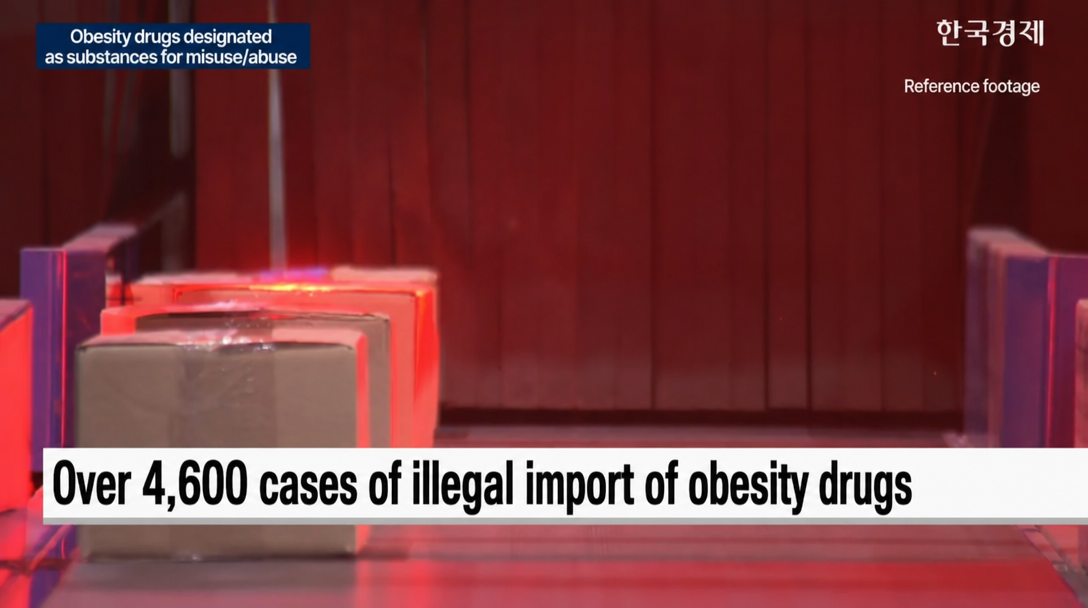 A news screen showing boxes of illegally imported obesity drugs moving along a conveyor belt.