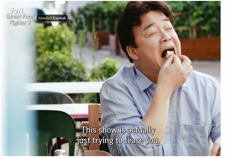 A screenshot of Baek Jong-won happily taking a big bite of bread topped with Kaymak.