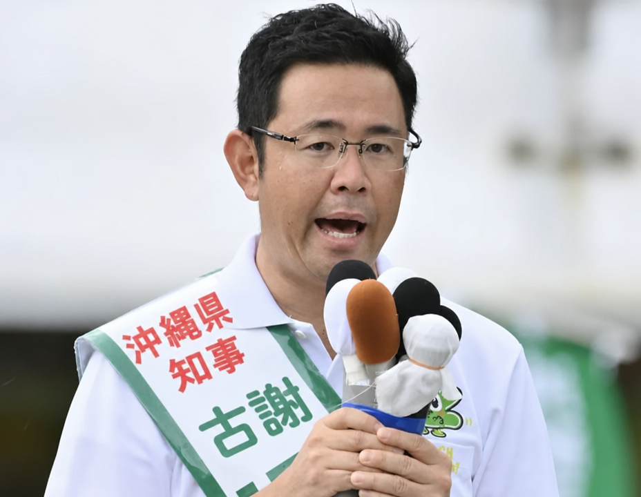 選挙たすきをかけ、マイクを持って発言するコザ・ゲンタ候補