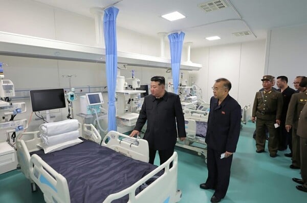North Korean leader Kim Jong-un inspecting hospital rooms and medical equipment with officials.
