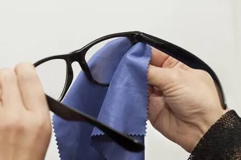 Two hands cleaning glasses lenses with a microfiber cloth