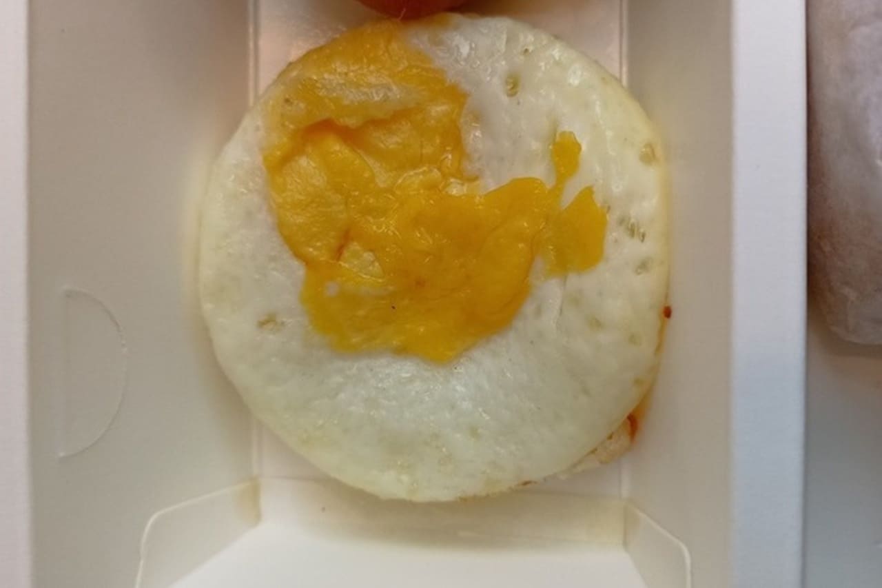 A processed fried egg with an unnaturally flat and perfectly round mold-like shape.