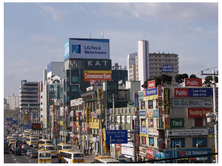 Cluttered shop signs on a street in early 2000s Seoul, along with city buses and cars from that era.