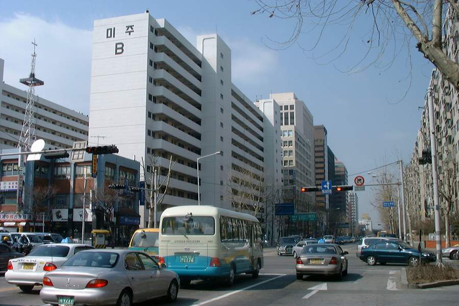An EF Sonata and an old town bus driving on a road in the early 2000s, with apartment buildings in the background.