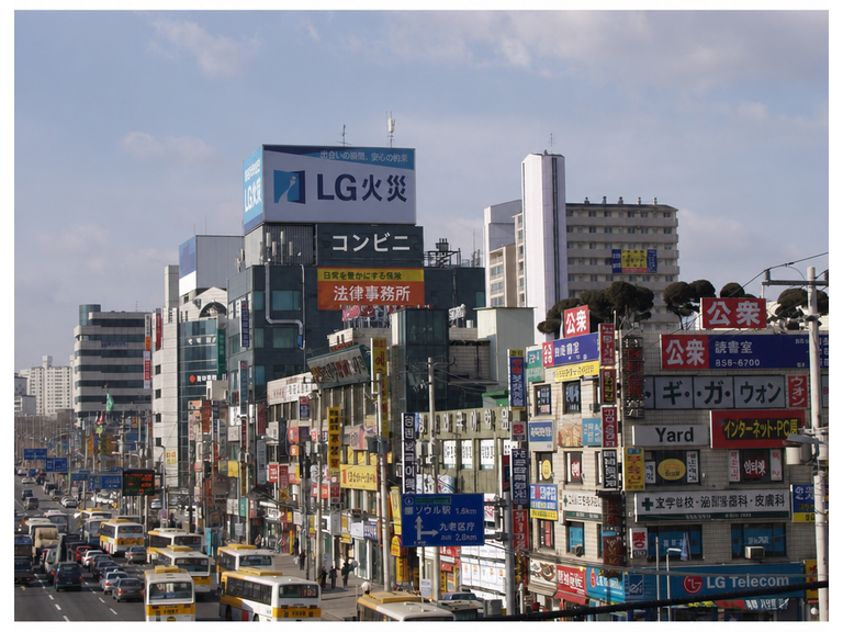 2000年代初頭のソウルの繁華街にひしめく看板と、当時の市内バスや車の風景。