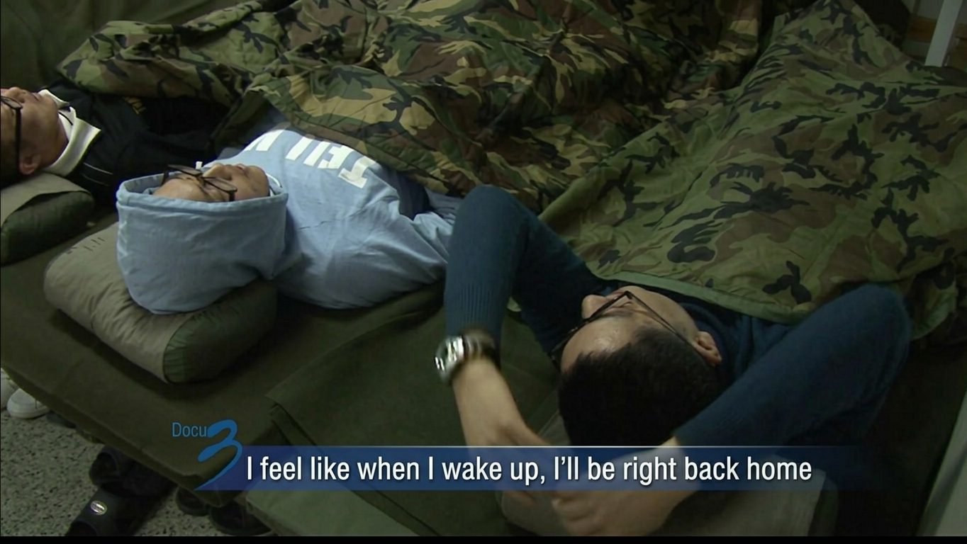 Recruits lying on barracks mattresses covered with camo sleeping bags