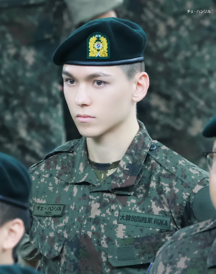 軍服とベレー帽を身につけ、正面を見つめるSEVENTEENのバーノンの姿。
