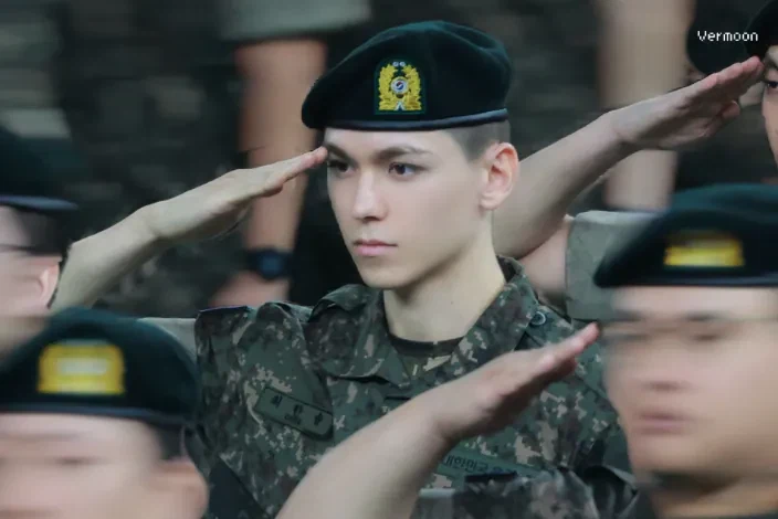 軍服を着た訓練兵たちの中で敬礼をしているSEVENTEENのバーノン。