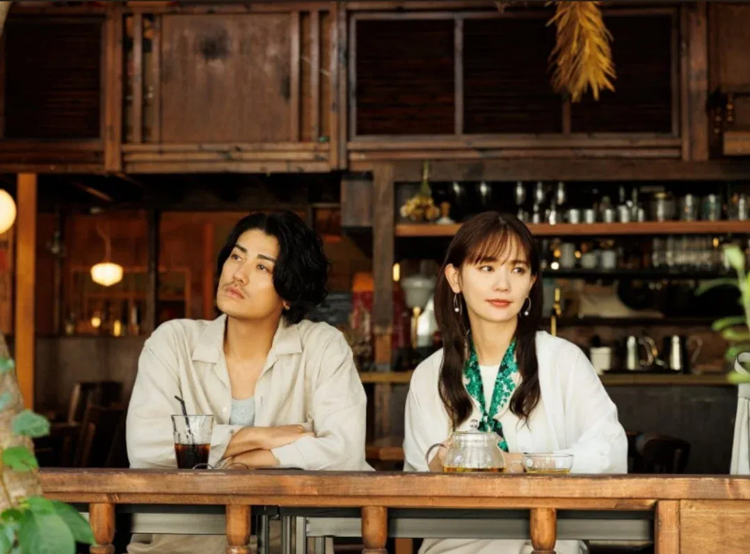 A scene from a drama showing Yuri Nakamura sitting with the cast