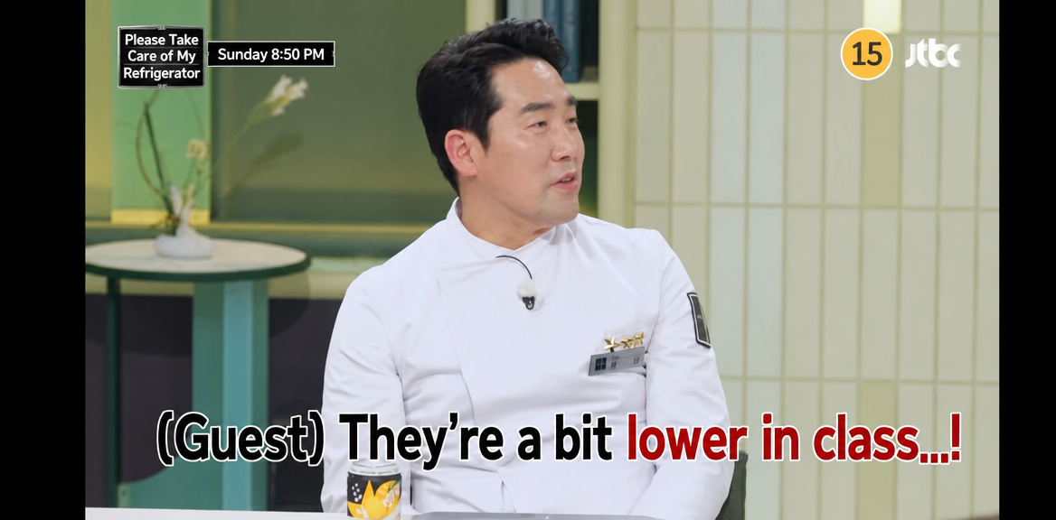 A broadcast screenshot of Chef Sam Kim sitting in his chef's uniform, making a playful comment to the guests: 'They're a bit lower in class...!'