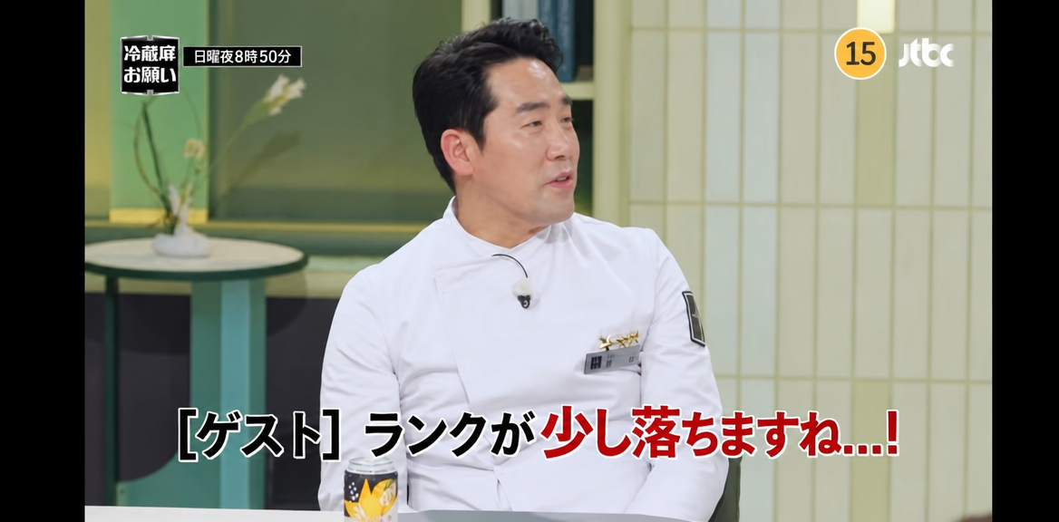 シェフ服を着て座り、ゲストに向かって「ランクが少し落ちますね…！」といたずらっぽくコメントを飛ばすサム・キムシェフの放送画面キャプチャー。