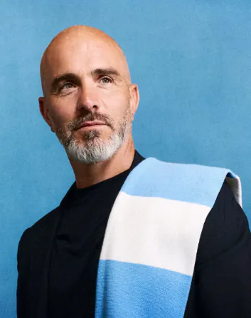 Profile picture of a bald, bearded man wearing a light blue and white striped muffler