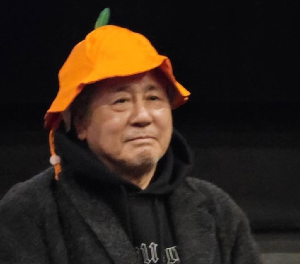 Actor Choi Min-sik giving a stage greeting wearing a tangerine-shaped hat