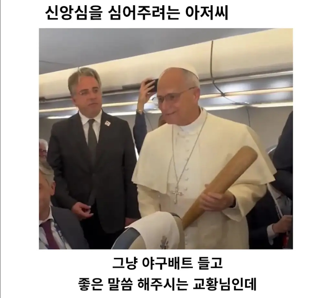 The Pope standing in an airplane aisle wearing his papal vestments, holding a wooden baseball bat, and smiling.