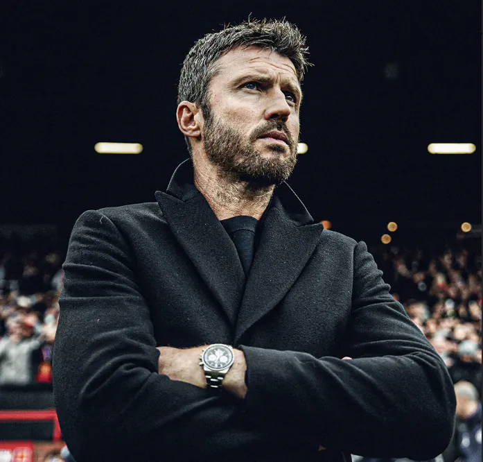 Michael Carrick, the soccer manager, with his arms crossed and a serious expression.