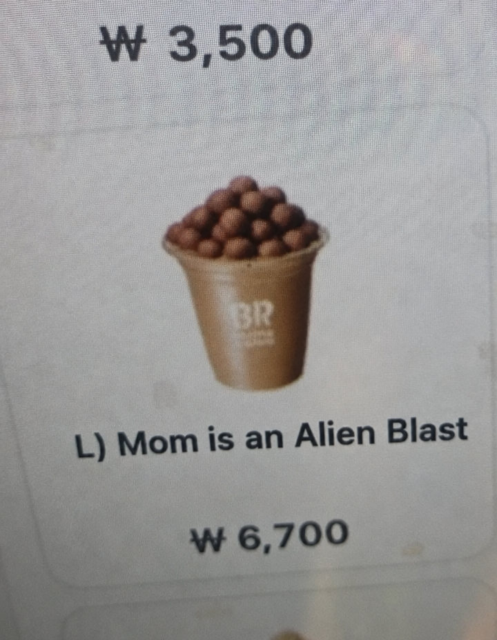 Baskin Robbins kiosk screen showing a photo of the 'L) Mom is an Alien Blast' menu item, with a large pile of chocolate balls on top of the cup.