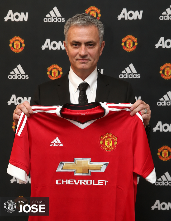 Manager José Mourinho posing for a photo while holding a Manchester United jersey.