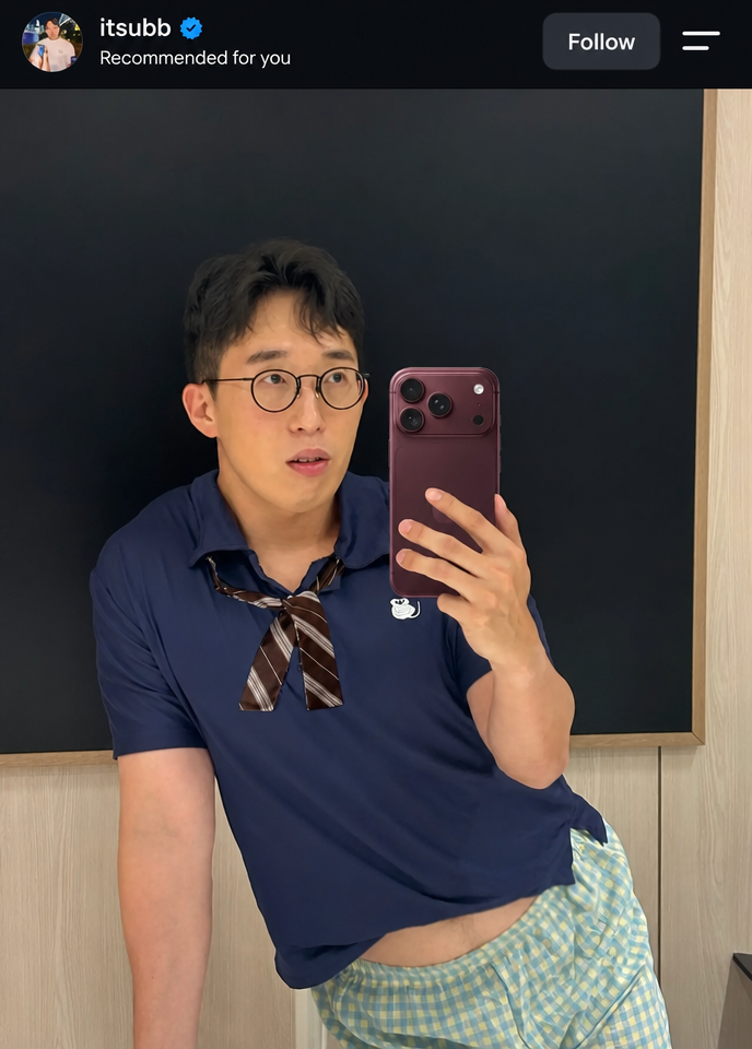 YouTuber ITSUBB taking a mirror selfie in checkered shorts and a ribbon tie, with his waist slightly exposed