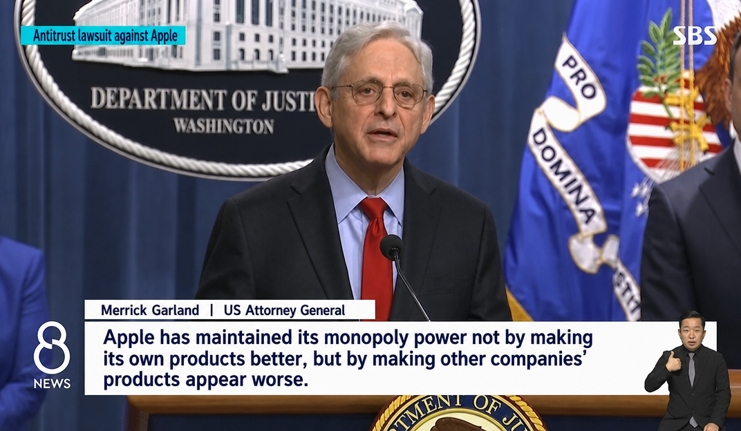 A news screen capture of US Attorney General Merrick Garland speaking at a press conference regarding the Apple antitrust lawsuit.