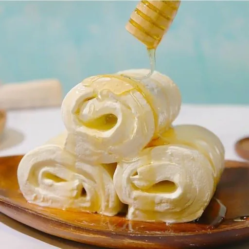 A white, round rolled kaymak topped with honey