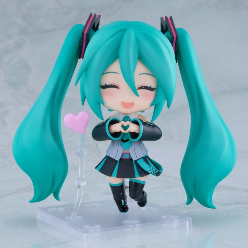 Hatsune Miku Nendoroid figure smiling and making a hand heart.