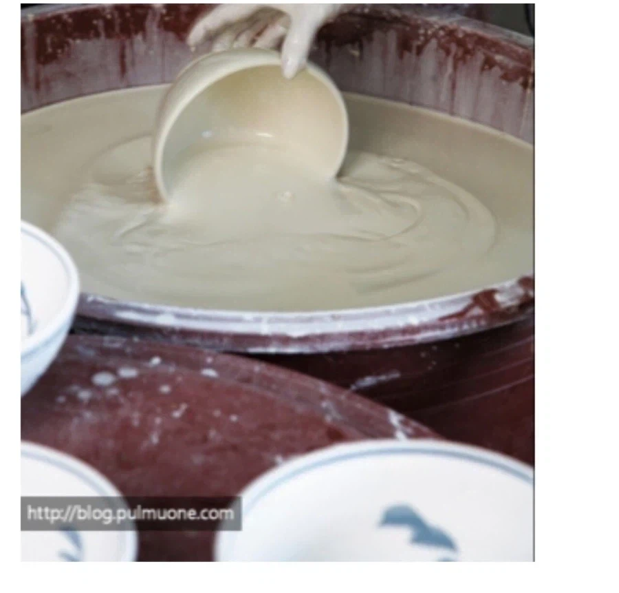 Pottery glazing process of submerging a bisque-fired ceramic vessel into a basin filled with thick white glaze
