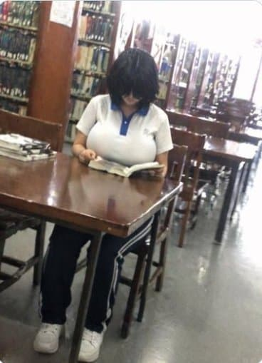 図書館の机に座り、前髪で目を隠したまま本を読んでいるショートカットの女性