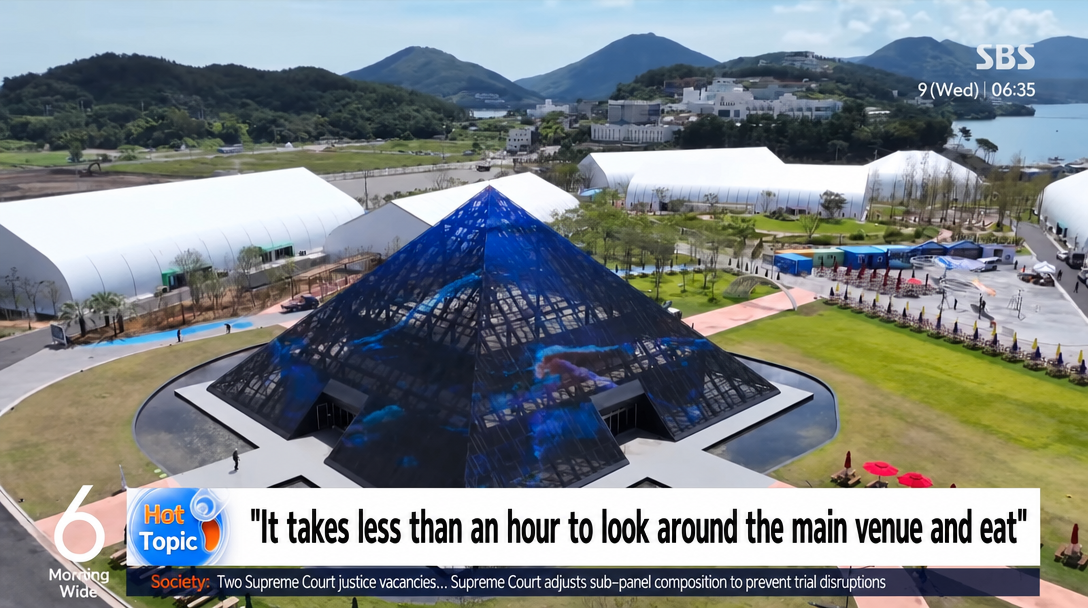 SBS news screen showing a pyramid-shaped structure at the venue with the caption 'It takes less than an hour to look around the main venue and eat'.