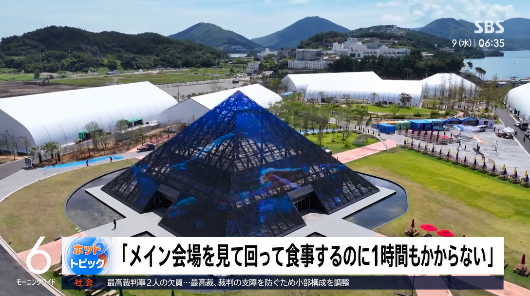 SBSニュース画面に映る会場のピラミッド型建築物と「メイン会場を見て回って食事するのに1時間もかからない」という字幕。