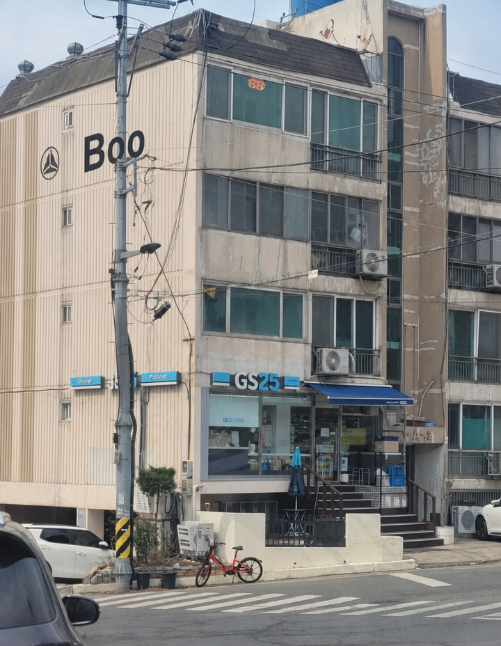A photo of a GS25 convenience store set up in the first-floor residential space of an old low-rise apartment or villa building, featuring stairs and full glass windows.
