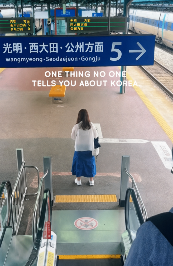 駅のエスカレーターを降りてすぐ、出口前の通路中央でポツンと立っている乗客の後ろ姿。