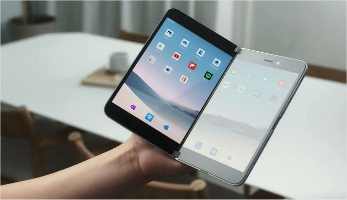 机の上で斜めに開かれたSurface Duoを手で持っている様子